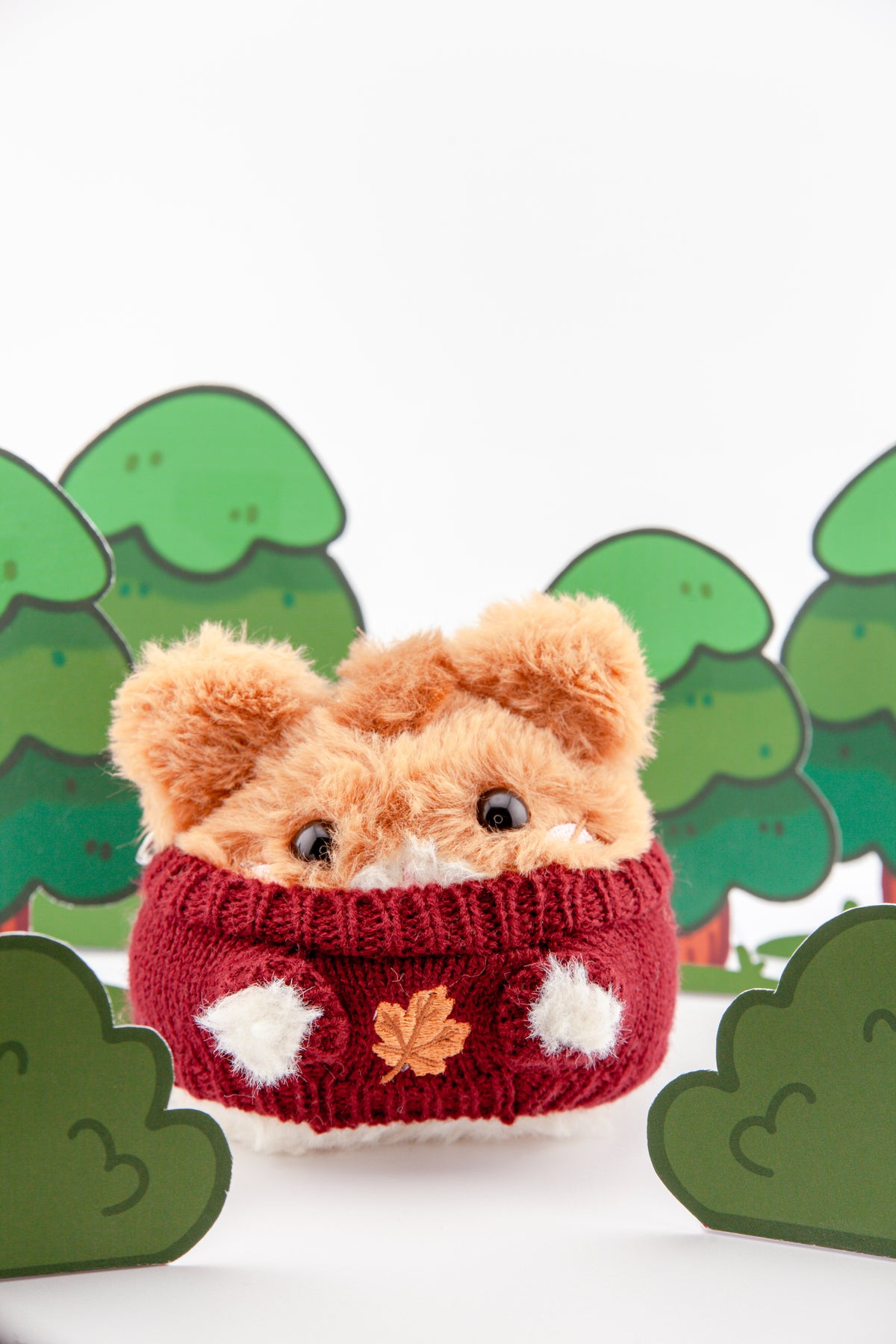 A Bellinghamster Plush wearing a cranberry red Maple Leaf Sweater for Bellinghamsters plush with embroidered golden autumn maple leaf